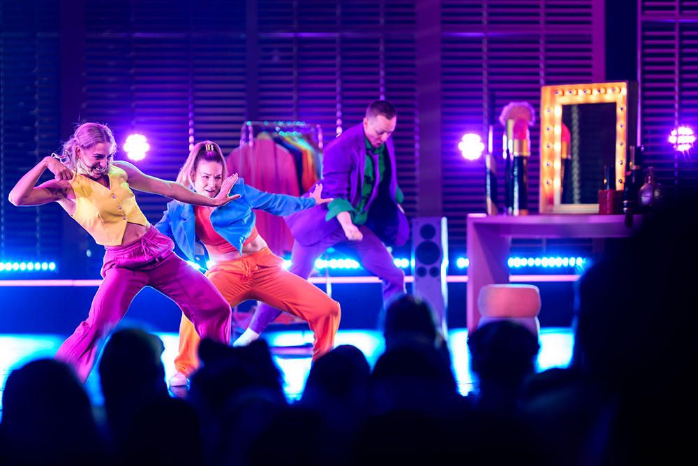 Drie kleurrijke dansers op een podium